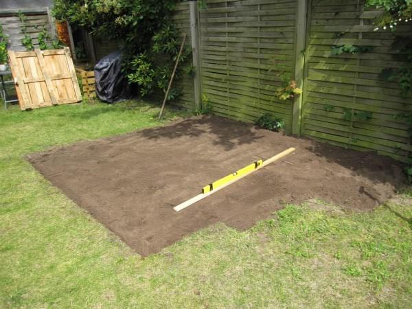 Préparation du terrain avant la construction de la terrasse en palette avec un niveau à bulle